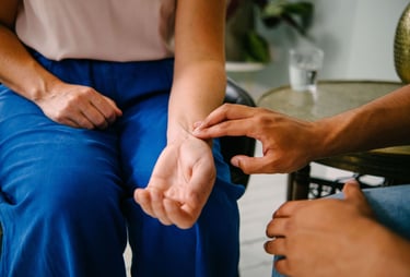 A healthcare professional checking a patient's pulse by hand on their wrist for a medical heart rate monitor check.