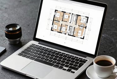 A professional photograph of a laptop displaying a complex architectural floor plan next to a cup of coffee on a clean, dark slate surface.