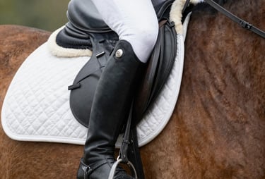 Elegant riding boots placed on hay with soft natural lighting
