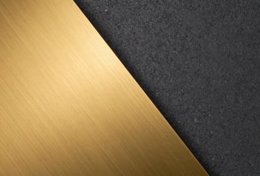 An abstract image showing the contrast between a smooth golden metal surface and a textured dark graphite wall, reflecting the brand colors.