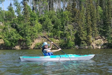 a woman in a blue shirt is kayaking on a lake