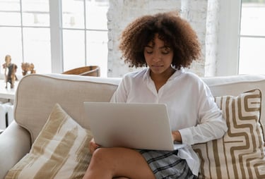 A single mom working on her side hustle on her laptop in her living room while her kid is in school.