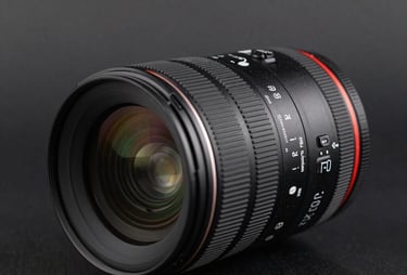 Close-up of a high-end camera lens on a black surface with subtle reflections in dark gray. Sharp focus under professional lighting. International / Professional.