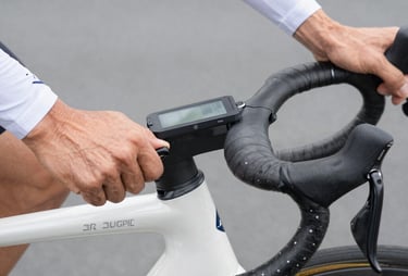 A close-up photograph of a dynamic cyclist setting up his sports computer on the handlebar, high technical precision, crisp clean lighting, white and slate grey tones.