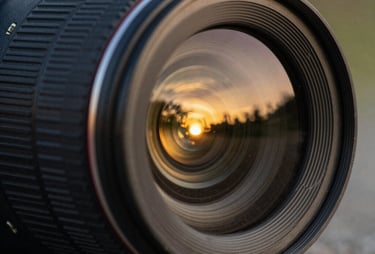 A close up of a camera lens reflecting a sunset. Warm golden colors, professional and artistic photography style.