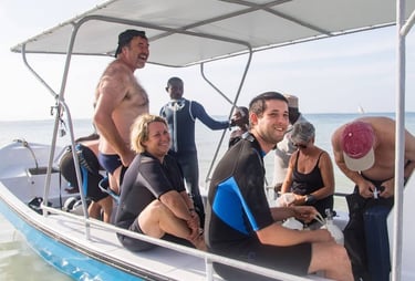 Smiling divers in wetsuits on a boat preparing for a scuba diving excursion in the ocean.