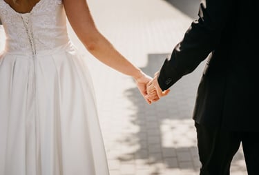 a bride and groom holding hands and walking down a path