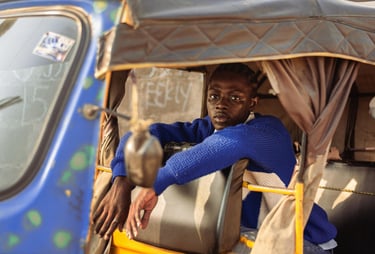 a man in a blue sweater sitting in a tuk tuk