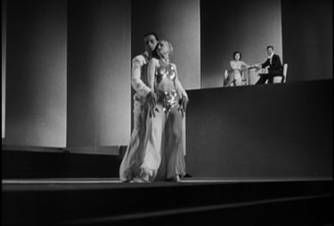 Surreal Busby Berkeley dance tableau of two white‑clad dancers framed by modernist geometric shapes.