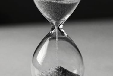 Close-up of an hourglass on a desk, the sand is flowing. High-contrast black and white style. Professional and philosophical. No people.