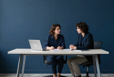 A minimalist office where a consultation is taking place. Clean, modern industrial aesthetic. Tones of deep navy blue and pale gray. General / Spanish-speaking.