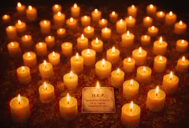 Many glowing memorial candles surround a commemorative plaque for migrants at a vigil.