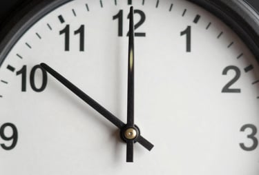 A close-up shot of an analog clock with a minimalist face and clean metal hands, set against a dark background. Symbolizing precision and time management.