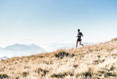 Coach de trail en montagne courant sur un sentier, illustrant le coaching course et trail en ligne