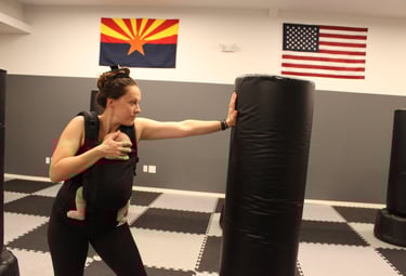 Instructor carrying baby and striking heavy bag
