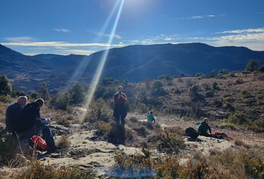 a group of people sitting and relaxing on a hill with a sun shining in the background