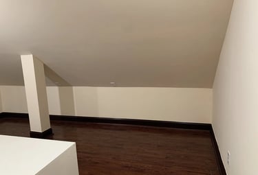 Empty attic room with new dark hardwood floors, light beige walls, and sloped ceiling