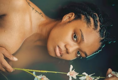 a woman with even-tone skin sitting in a bath of fresh aromatic herbs and spices