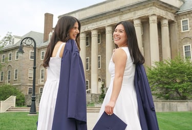 2 graduating seniors walking towards Old Main at Penn State.