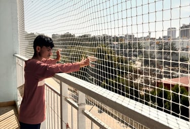 Close-up of hands inspecting the knots and mesh of a child safety net.