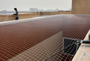 Technician inspecting and maintaining duct area nets on a rooftop in Bengaluru.
