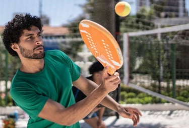 Praticante de beach tennis em movimento de forehand durante treino técnico na areia.