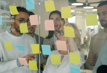 equipo de trabajo ordenando post-it sobre pared de cristal