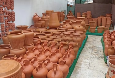 A wide variety of handmade terracotta clay pots, vases, and planters displayed at an outdoor pottery market.