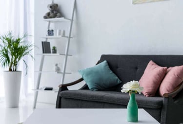 Modern living room with a white coffee table, grey sofa, and leaning ladder bookshelf decor.