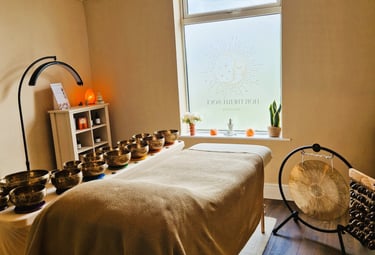 Treatment couch with singing bowls laid on a table, gong and seed chimes