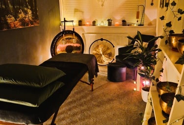Studio with treatment couch, chair, gongs and shelf with Himalayan singing bowls