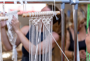 Taller con hilos en color blanco, haciendo una artesanía de macramé