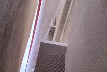 Technician installing a pigeon net on a high-rise apartment balcony.