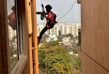 Technician installing a pigeon net on a high-rise apartment balcony in Chennai.