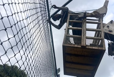 Hands tying knots on durable netting material, showcasing the craftsmanship behind each installation