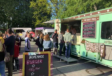 Customers lining up at a green gourmet food truck serving homemade burgers on brioche buns.