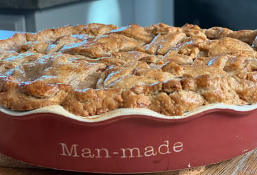 Freshly baked golden brown apple pie with a lattice crust in a red ceramic Man-made dish.