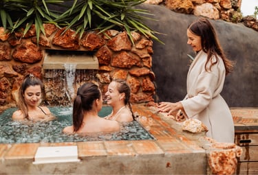 women laughing in a bathtub with a woman guiding them