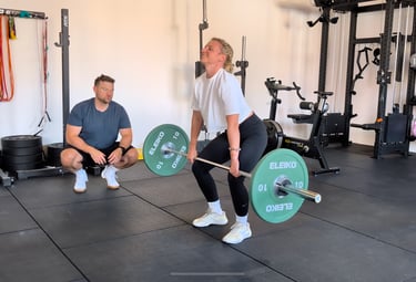 Eine Frau beim Kreuzheben mit Langhantel unter Anleitung eines Personal Trainers in einem Bielefeld