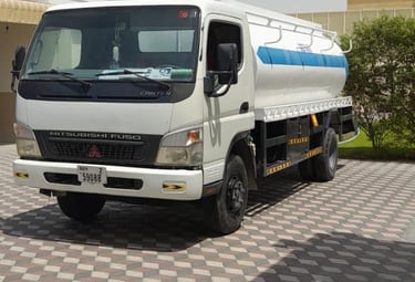 a truck with a tanker truck parked in front of a building