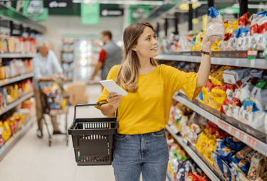 a woman in a yellow shirt is holding a shopping carton