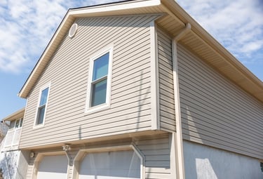 a house showing tan siding, white framed windows and tan gutters