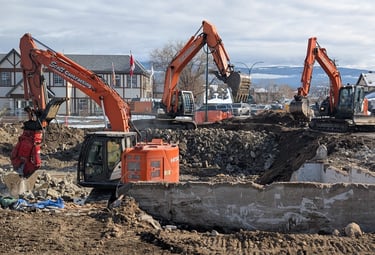 three excavators demolishing a commercial structure