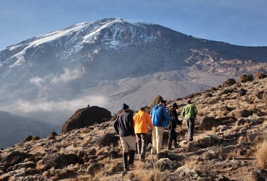 People hiking Kilimanjaro, with background of the mountain from a distance