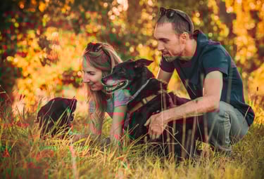 Ritratto di famiglia con due cani neri tra foglie gialle