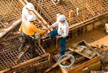 Ingenieros y técnicos revisando planos sobre estructura en obra, simbolizando asesoría y consultoría