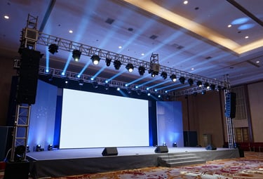 Large-scale corporate conference hall setup, grand stage design, precise structural framing, dramatic blue and white lighting.