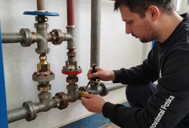 Technician fitting water pipes in a residential building under soft natural light.