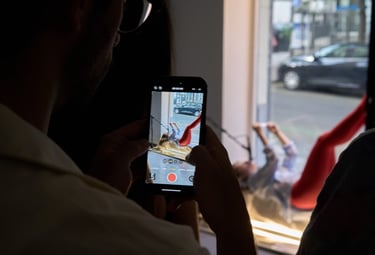 A person recording a smartphone video of a creative studio photoshoot with a model.