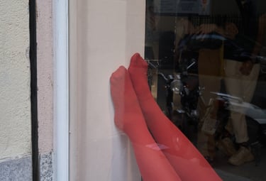A display featuring bright red sheer socks and leggings on mannequin legs in a store window.